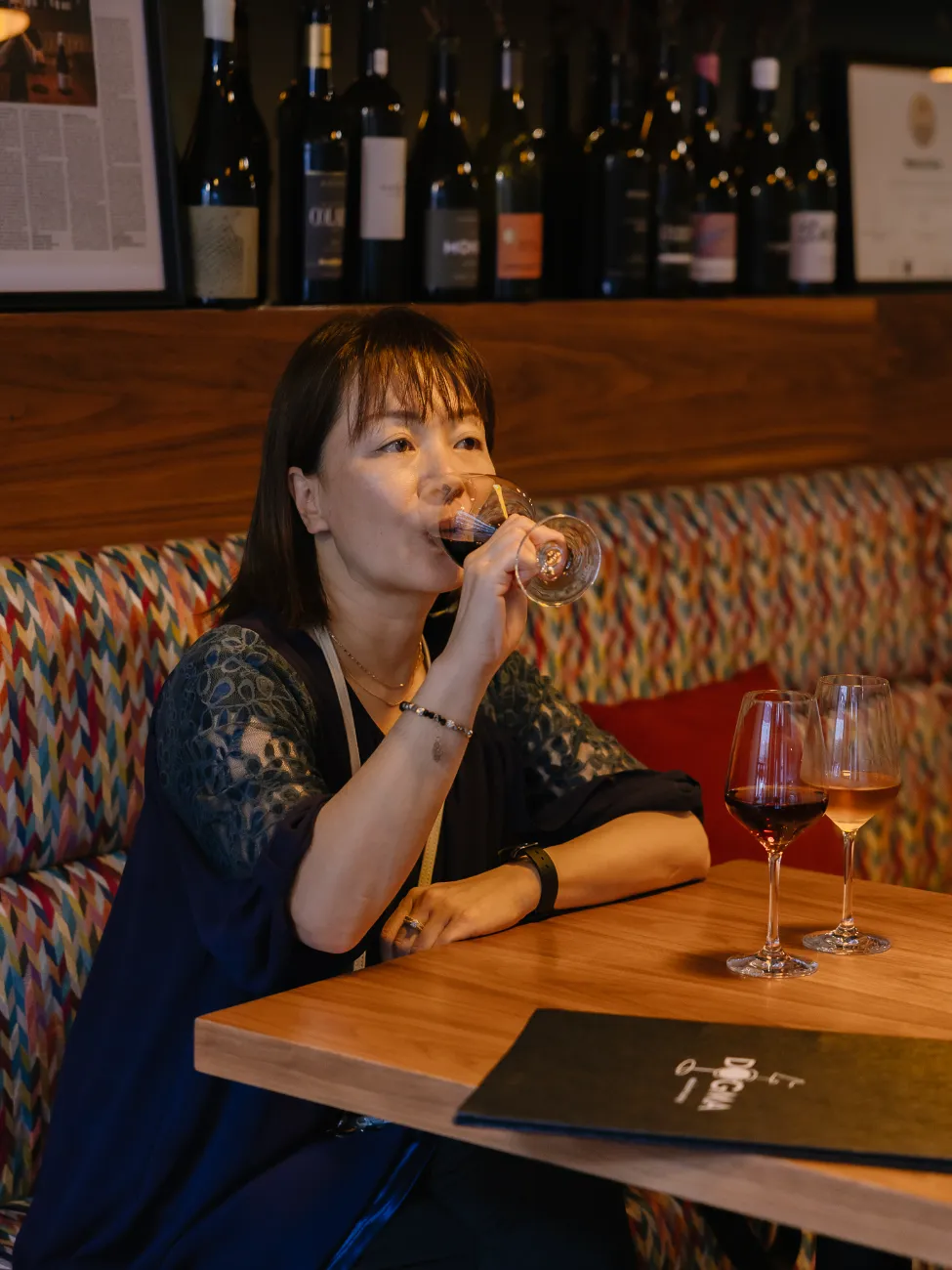 A guest enjoying a glass at the colourful banquette