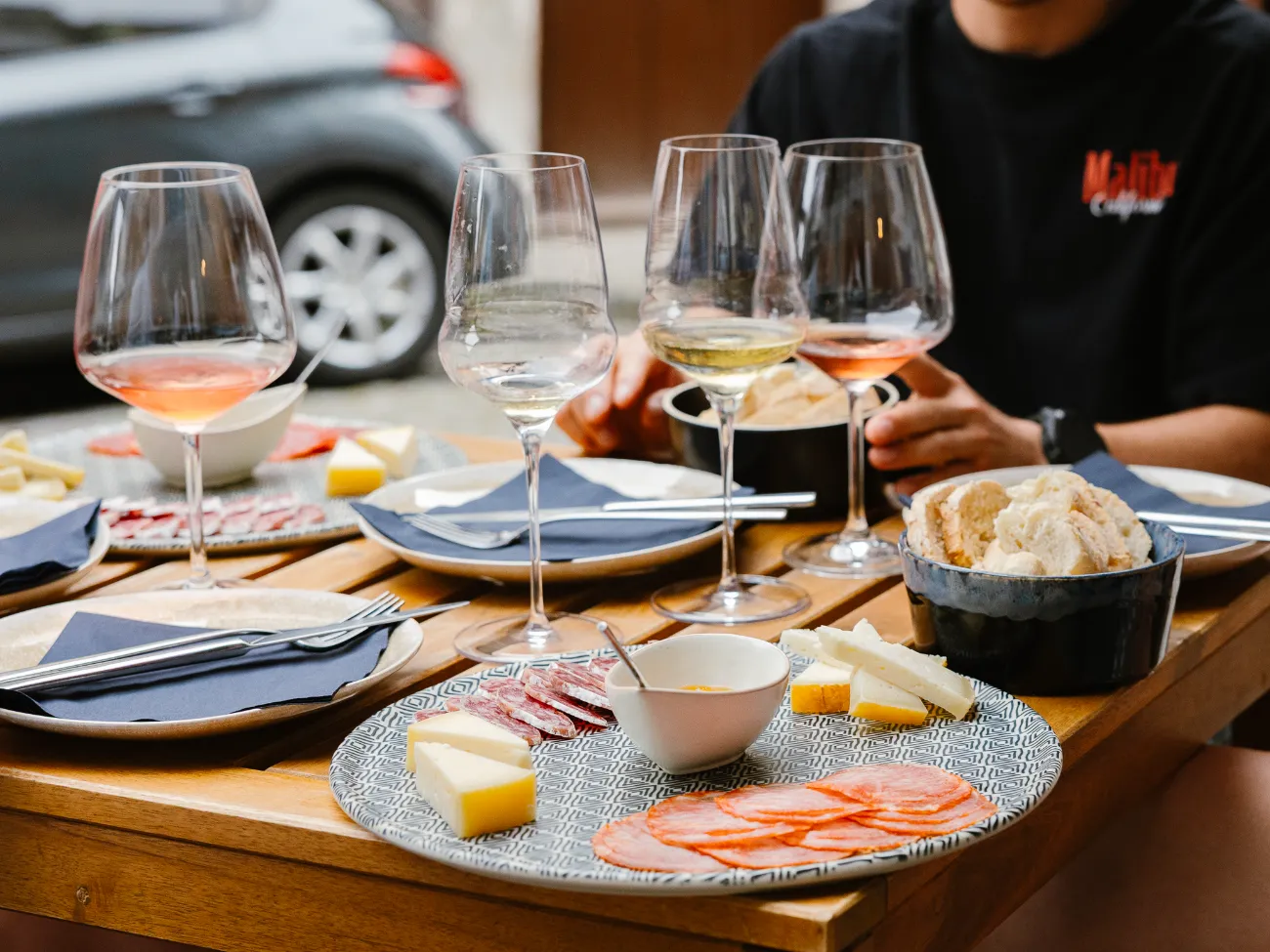 A spread of petiscos — charcuterie, cheese and crudo with wine