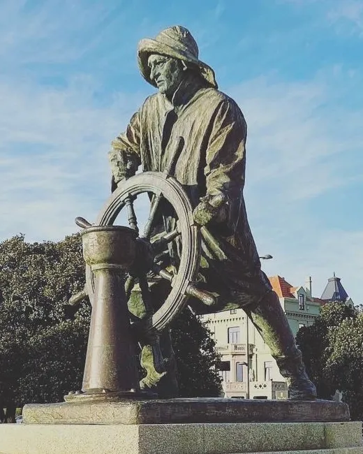 Bronze statue of a Portuguese helmsman against the sky in Porto