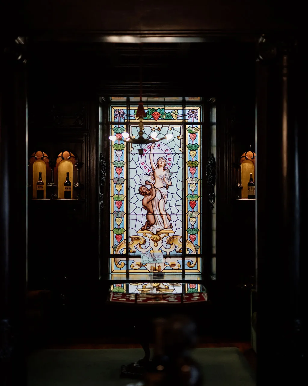 Stained-glass window glowing in a dark Porto wine lodge