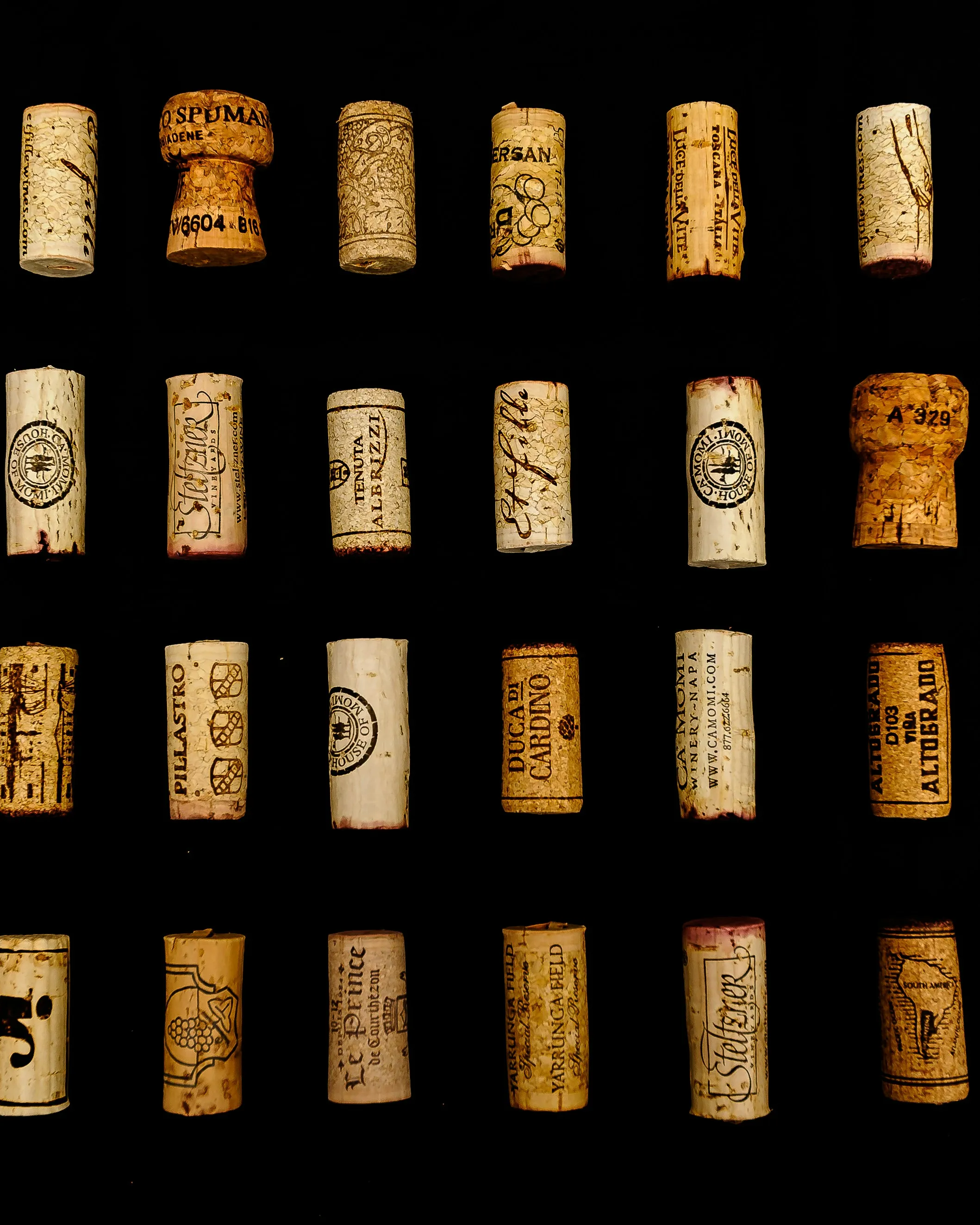 A grid of wine corks from estates around the world on black